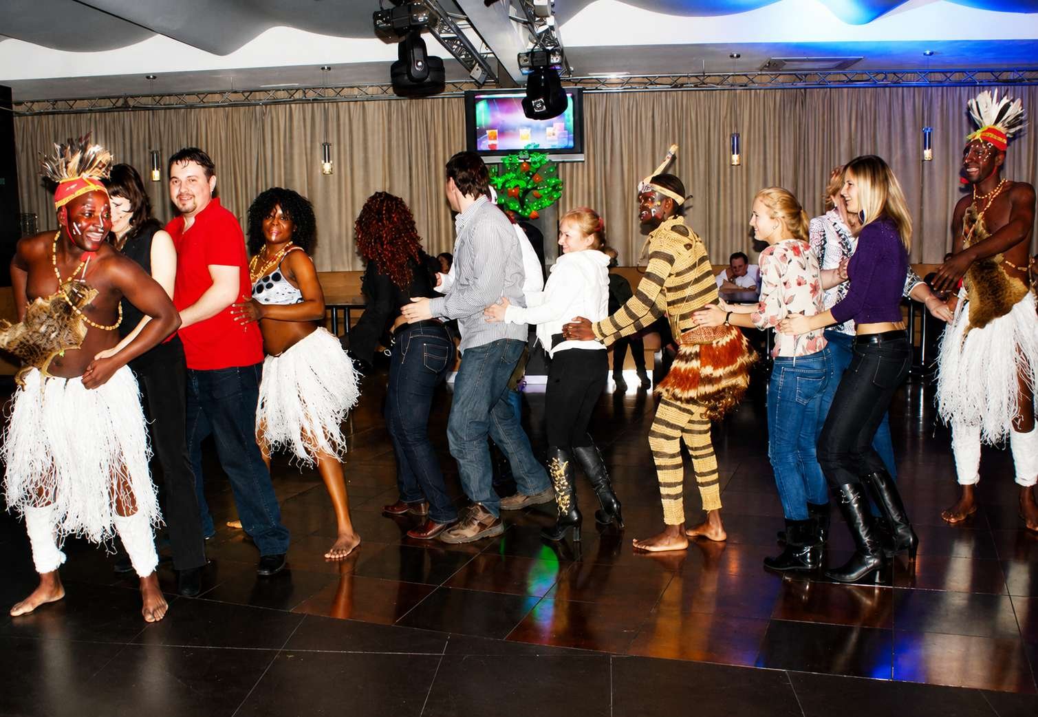 A group of people are energetically dancing in colorful, animal-inspired costumes at a lively party.
AI-generated content may be incorrect.